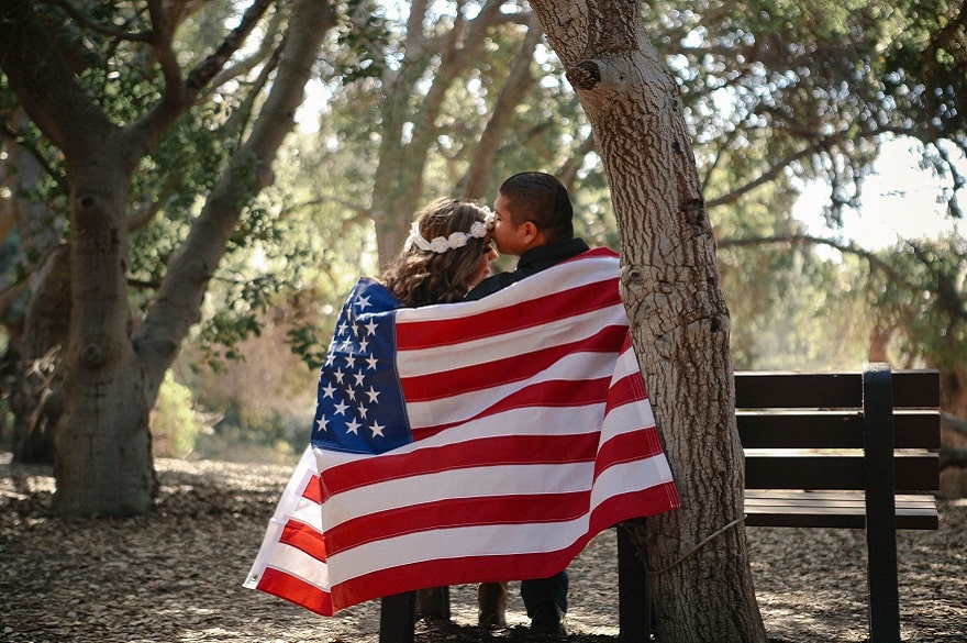 Best Items Made in the USA to Add to Your Registry, a couple standing outside, holding an American flag.